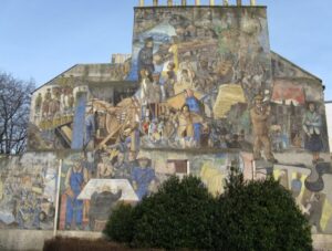 Side of building covered in a mural with many people