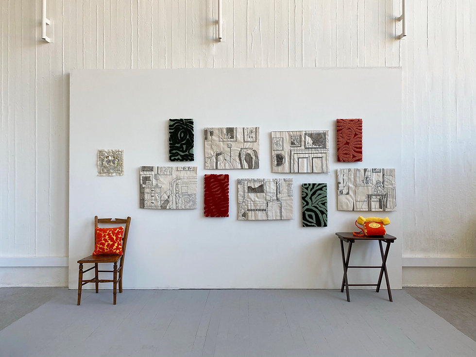 a chair with a red and yellow cushion on it, a table with a knitted red and yellow telephone on it, and a display wall with various patterned artworks hanging on it