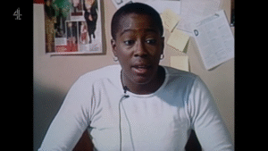 Screenshot from the film 'The Watermelon Woman' showing a black women in white top speaking directly to camera.