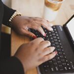 A persons hands on a laptop keyboard