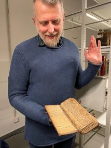 Peter Smolak holding a Hebrew book from Freie Universitat Berlin's collections