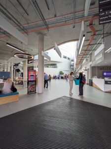 Light-filled internal view of academic building. LILAC 2026 conference attendees greet each other in the background.