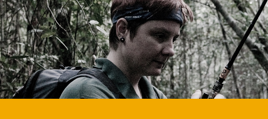 Susan Cheyne is photographed in a forest holding a handheld transceiver.