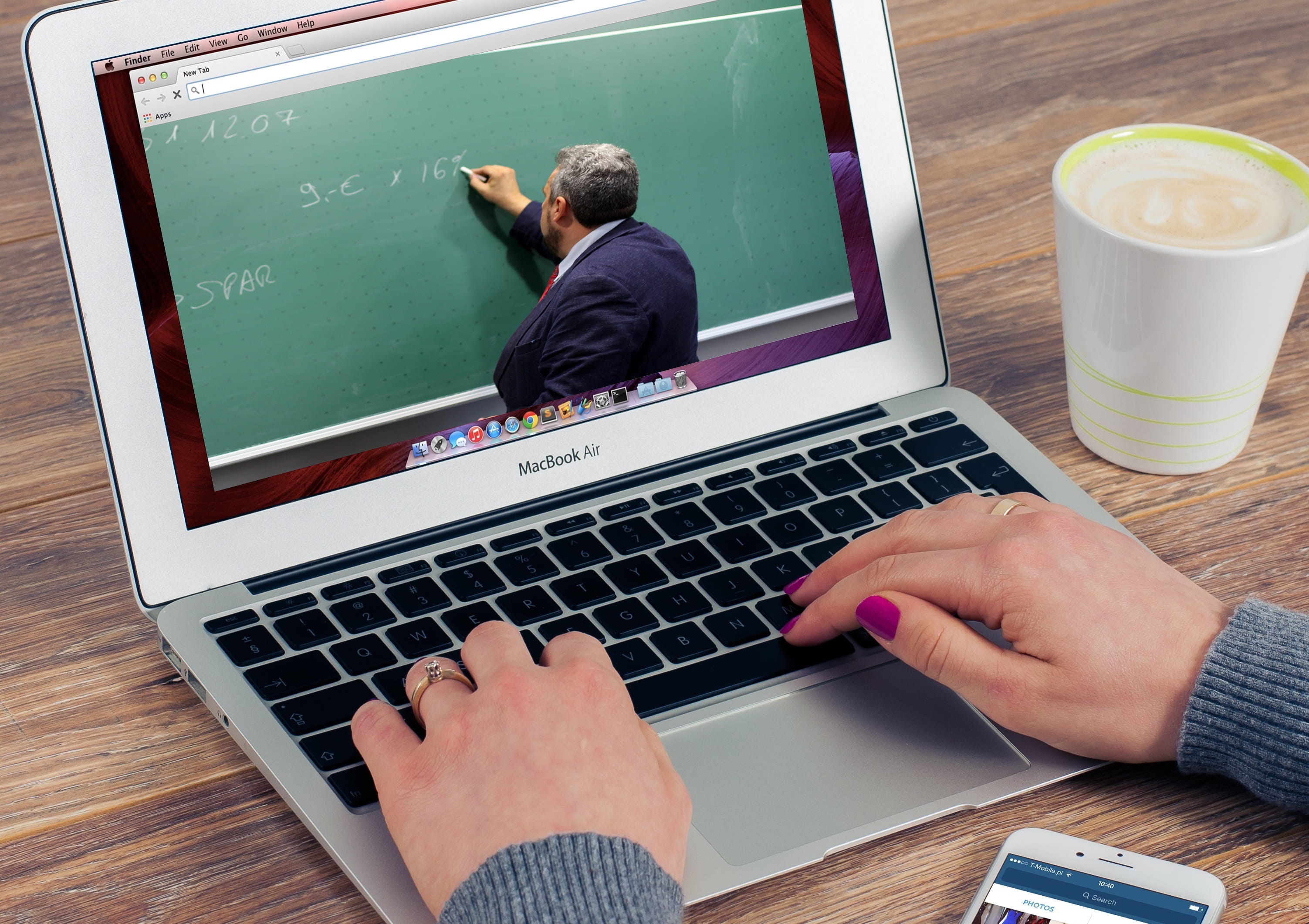 Photo of a laptop showing the back of a teacher writing on a blackboard