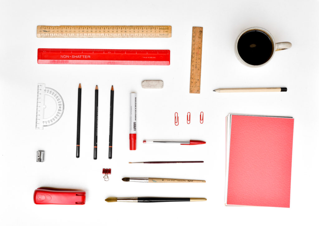 Coffee mug, pens, pencils, rulers, and paperclips, all arranged very neatly 