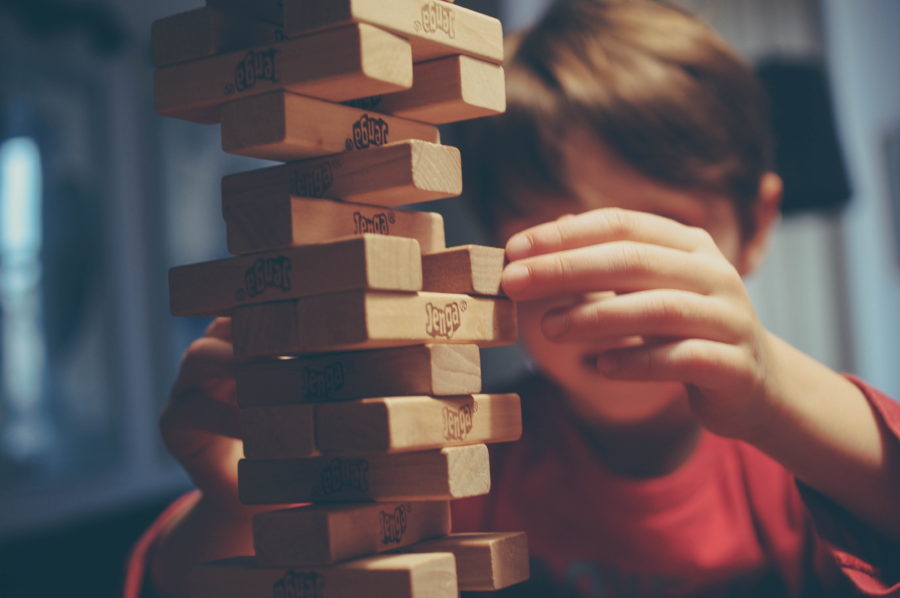 A boy with a tower of Jenga blocks