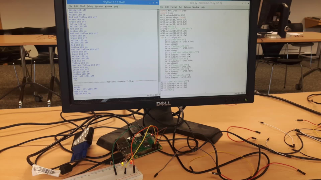 Raspberry Pi, breadboard with circuit, and monitor showing Python program code and text output