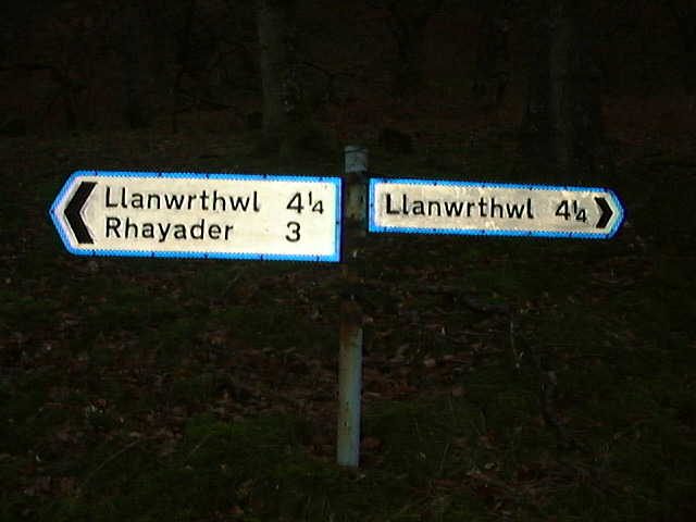 Two road signs pointing to the same location in opposite directions