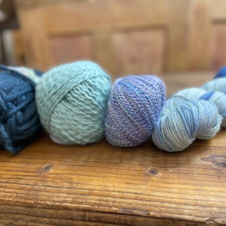 Various balls of yarn of different weights in shades of blue