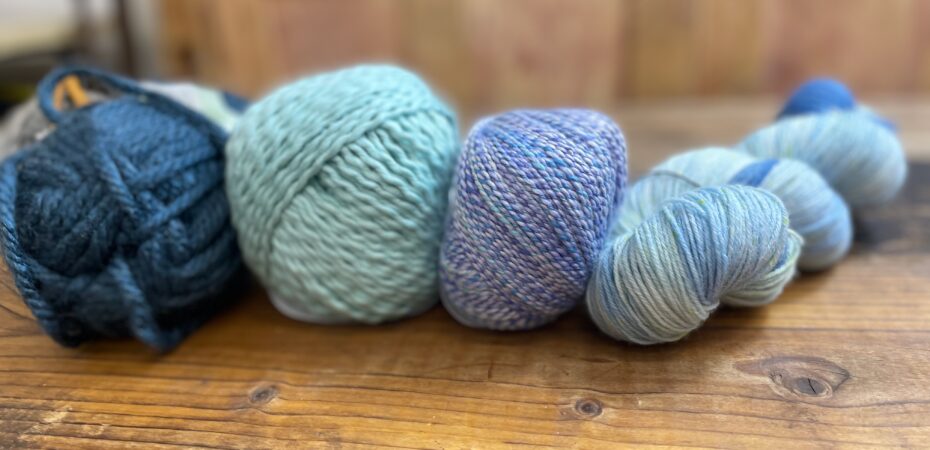 Various balls of yarn of different weights in shades of blue
