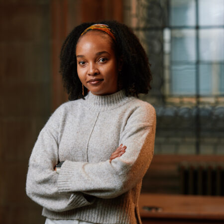 A photograph of Pepita with arms folded in a grey jumper, taken by Andrew Perry
