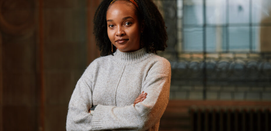 A photograph of Pepita with arms folded in a grey jumper, taken by Andrew Perry