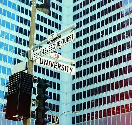 Tall buildings in city with street sign pointing to University