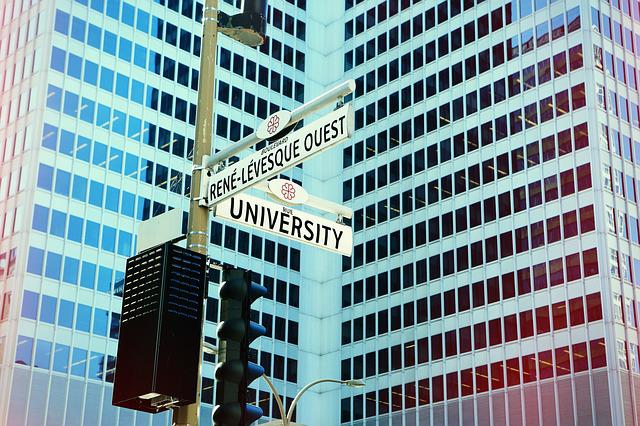Tall buildings in city with street sign pointing to University