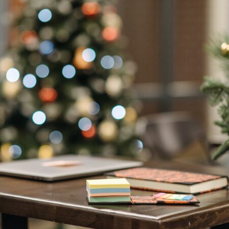 Notebook and laptop on a desk with a Christmas tree on the background
