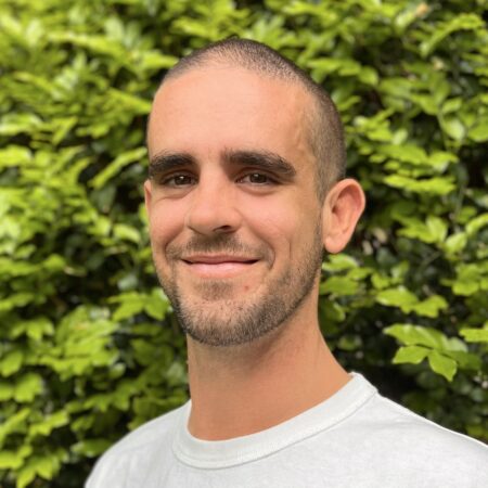 Headshot of man infront of a green bush