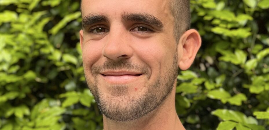 Headshot of man infront of a green bush