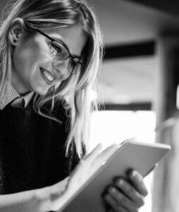 Smiling woman with glasses, using an iPad.