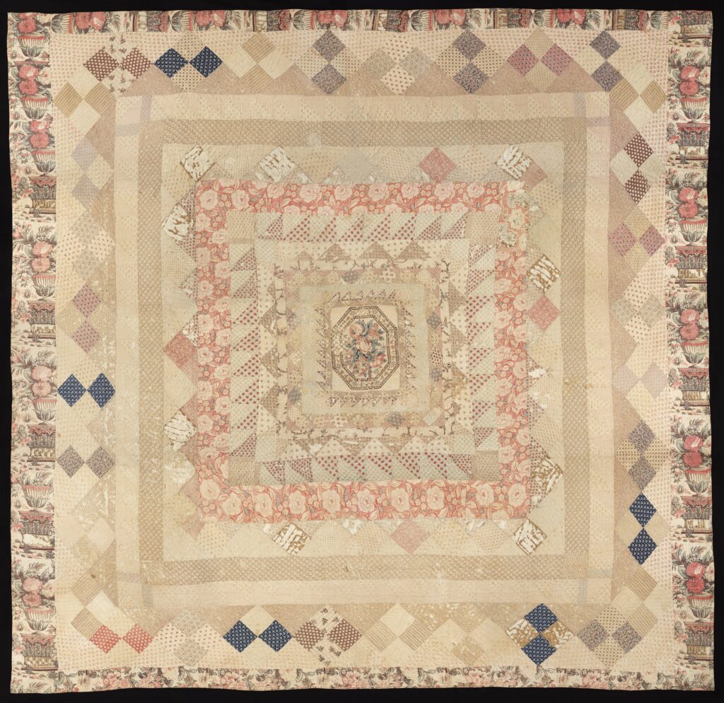Front of large, square patchwork quilt. Quilt design features a combination of floral and geometric motifs.