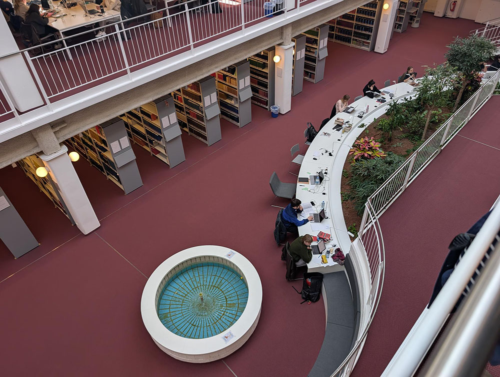 Internal view of the Freie Universität Berlin Campus Library, showing a water fountain and students studying at desks