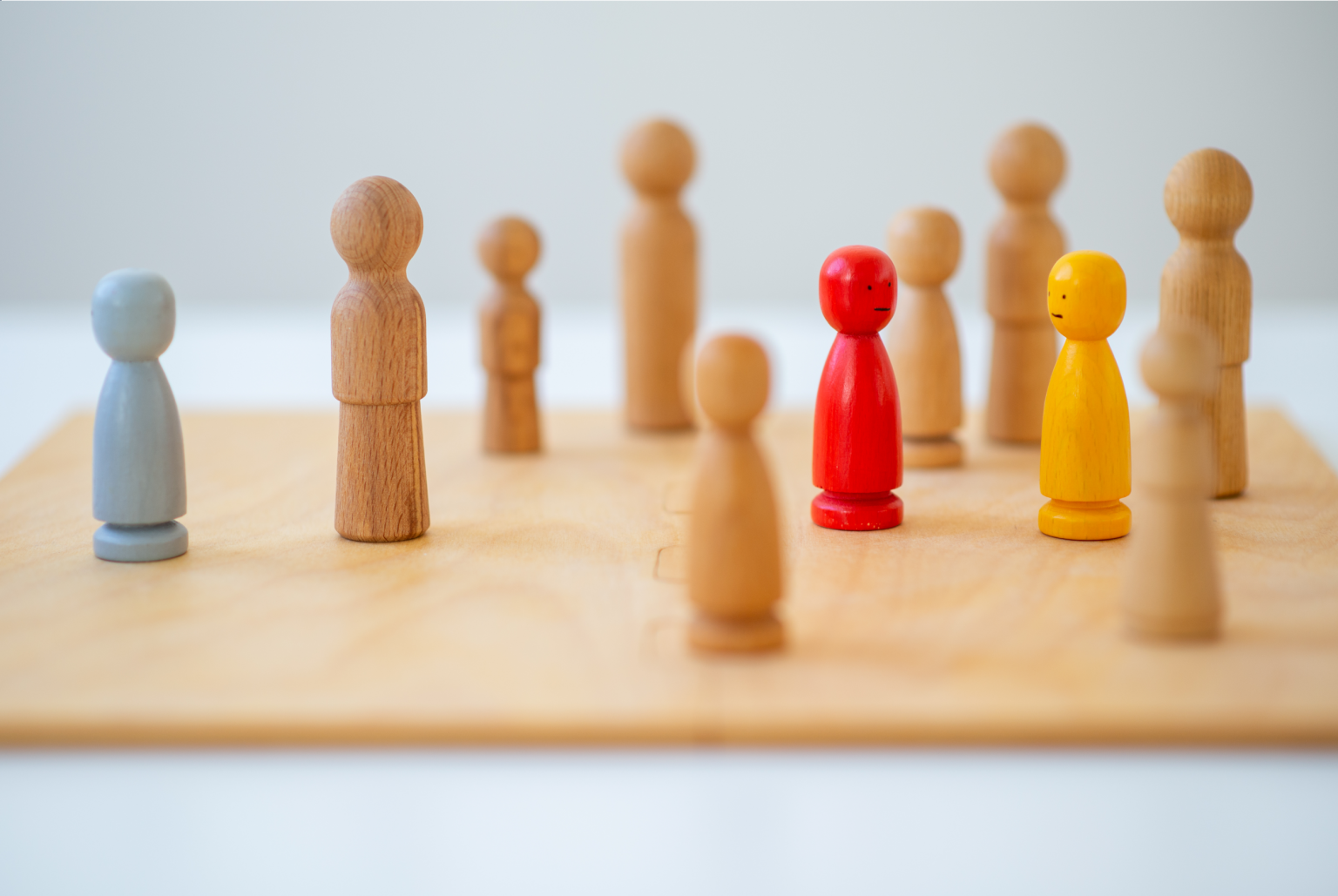 Image: An arrangement of wooden figures representing children and adults, some coloured.