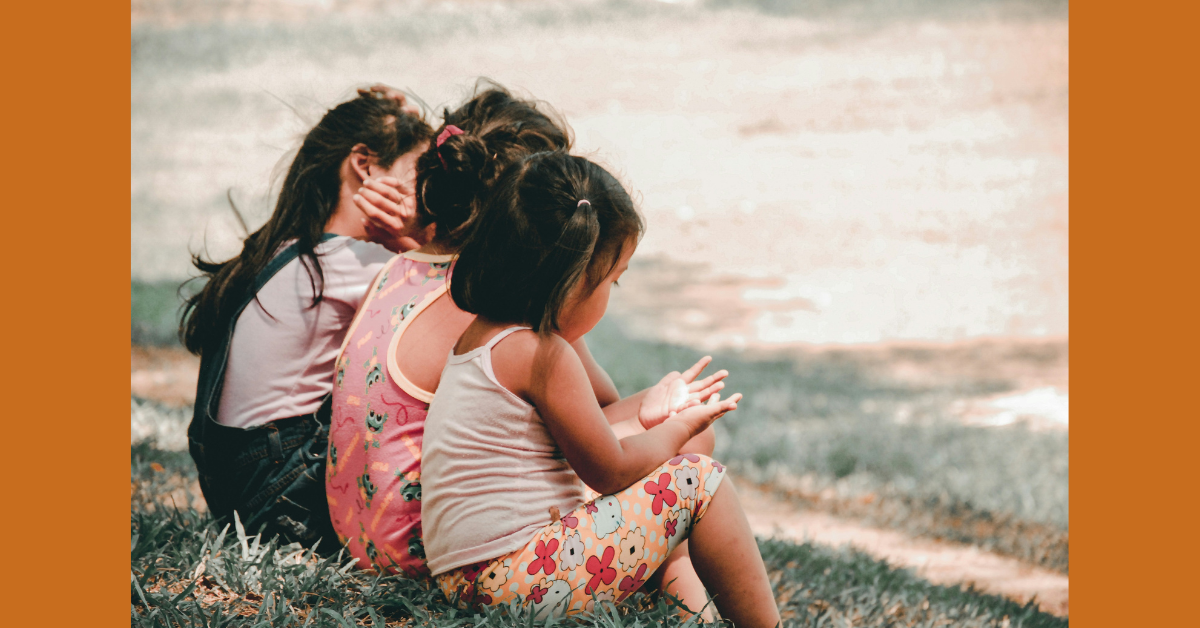 Three children sitting together on grass