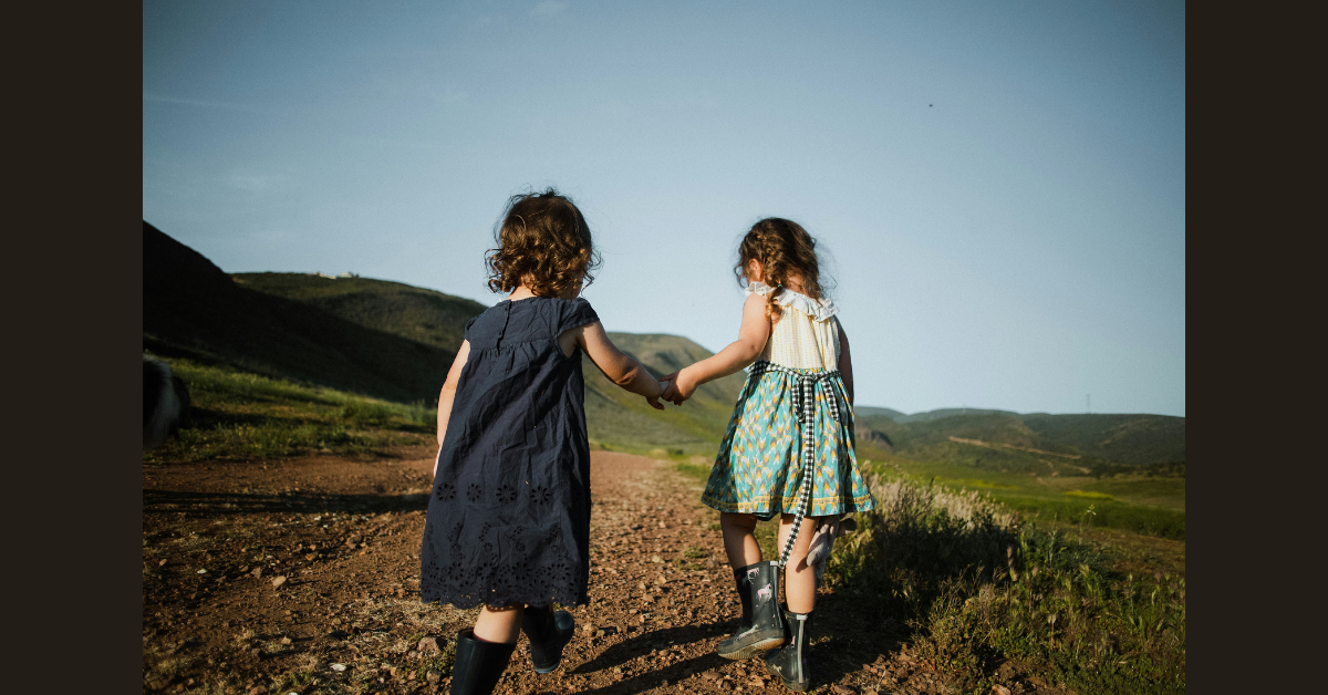 Two young girls walking hand-in-hand in the countryside