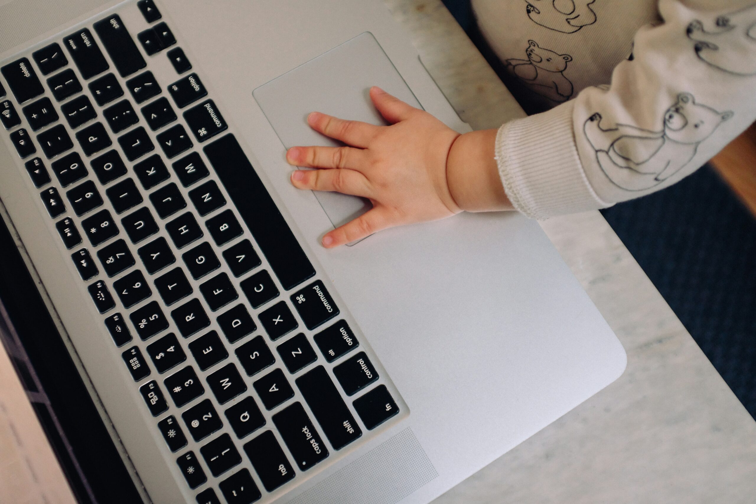 A toddler pressing the mouse pad of a laptop