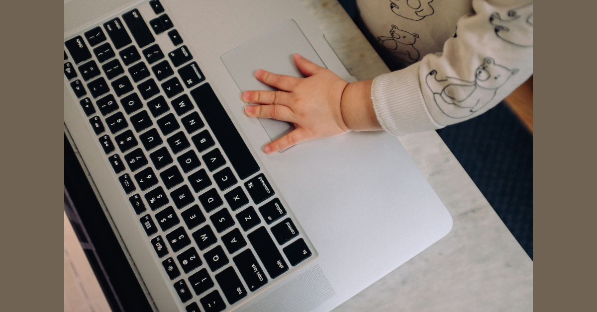 A toddler's hand on a laptop mousepad