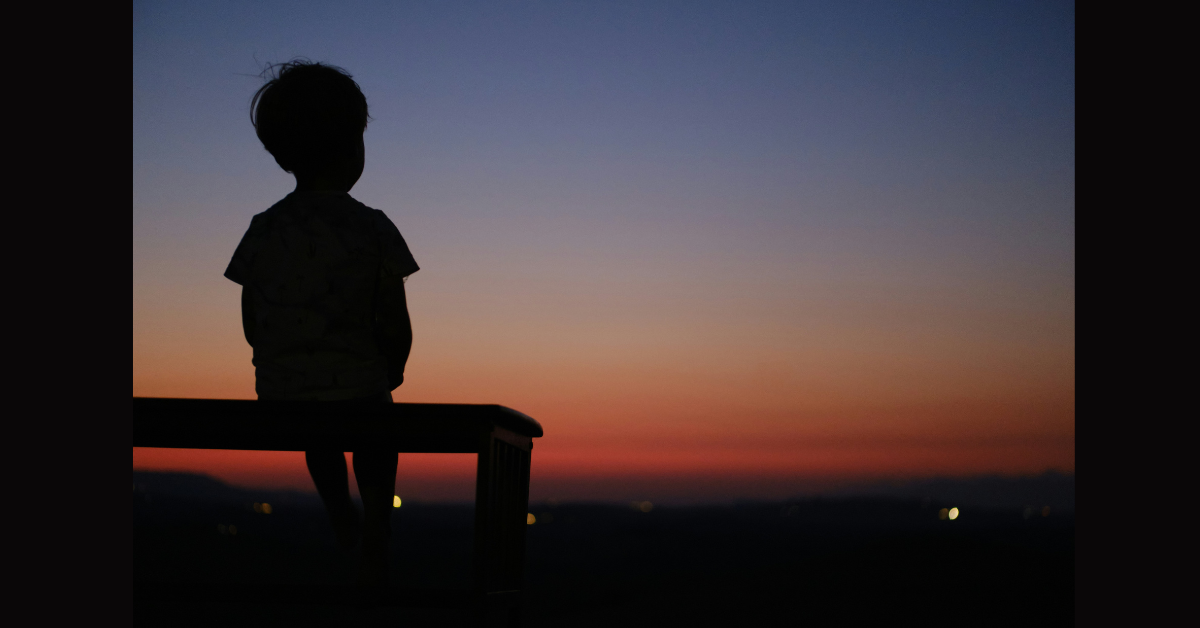 A child sitting on their own on a bench