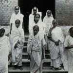 The Albert Victor asylum for lepers, Gohea, Calcutta, India: female patients in white saris on the steps of the female block. Photograph, 1900/1920.. Credit: Wellcome Collection. Attribution 4.0 International (CC BY 4.0)