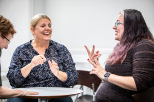 UoE staff laughing as they communicate using British Sign Language