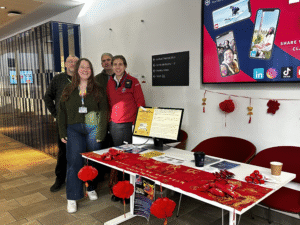 Angus and Gareth (back-row) and Ricarda and Mel (front frow) standing next to a table with lunar new year decoration and digital safety awareness leaflets