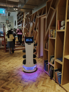 a waist-high cleaning robot in a cafe with cat ears and a monitor looking like a cat face