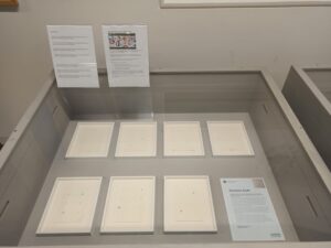 A picture of a library display of 7 artworks on paper