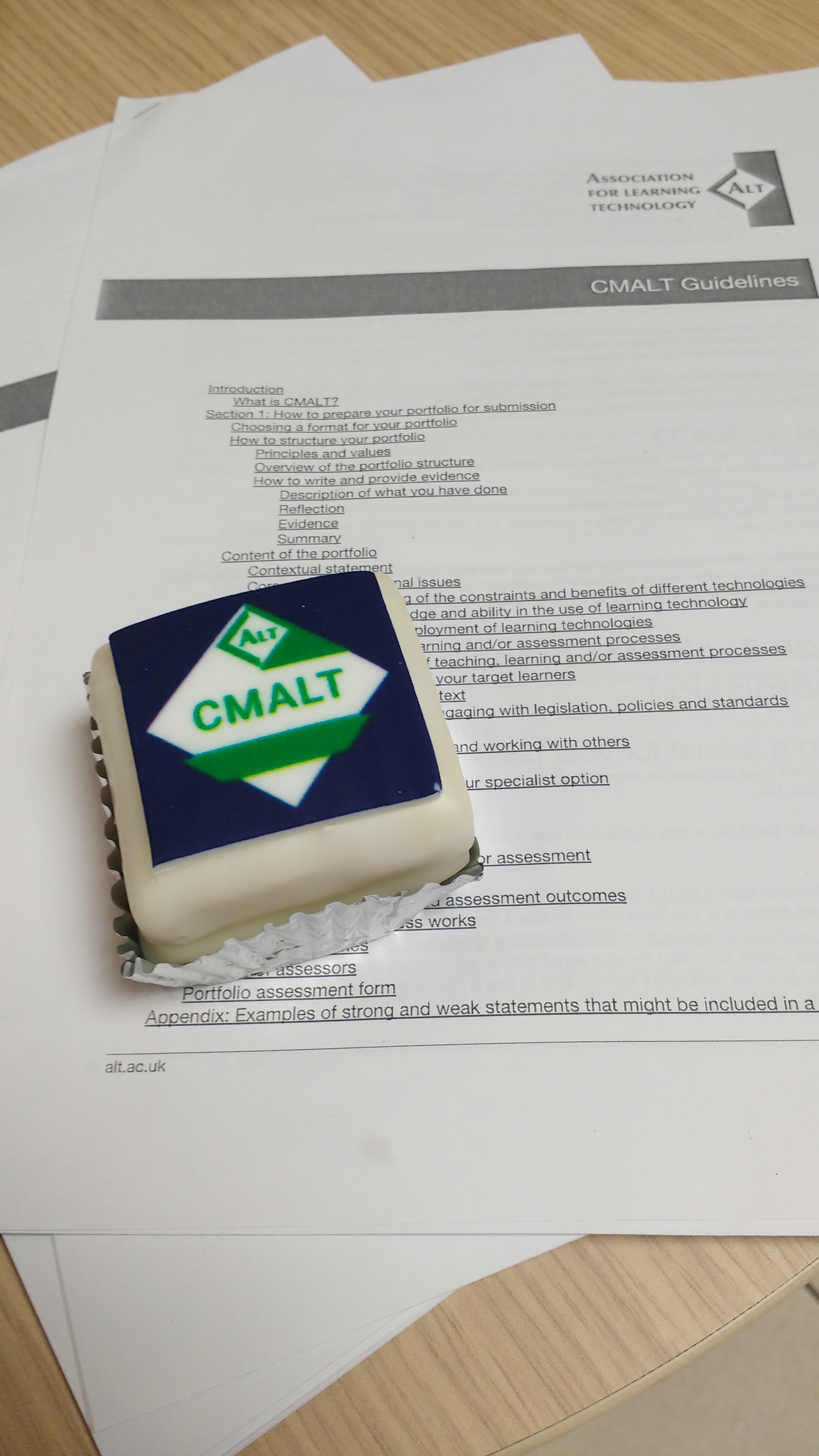 A photograph of the CMALT guideline documents and a cake with the CMALT logo