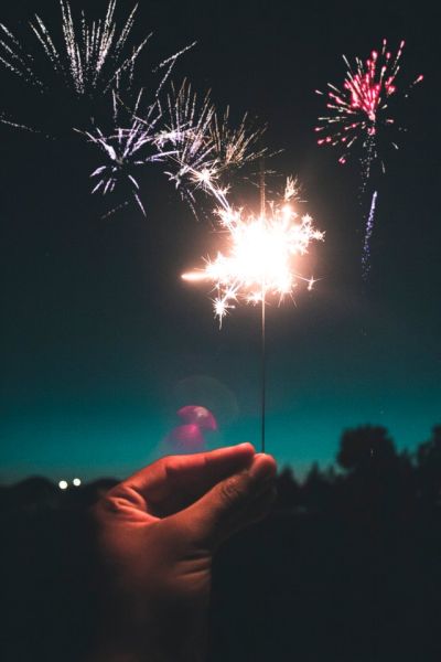 hand held sparkler against firework display