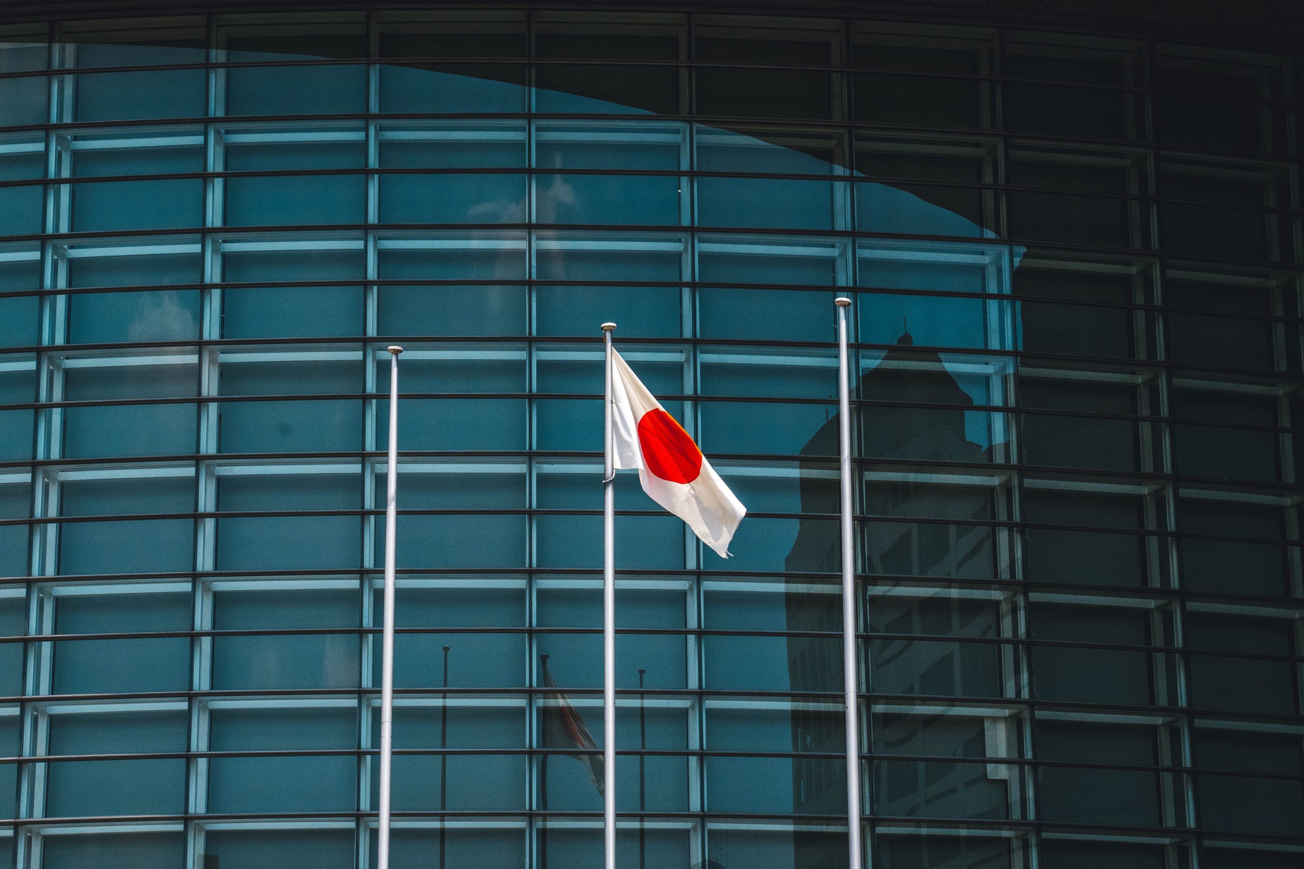 A colour photograph of Japan's flag in front of a modern building.
