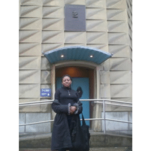 A graduate standing in front of a commemorative plaque of Charles Darwin