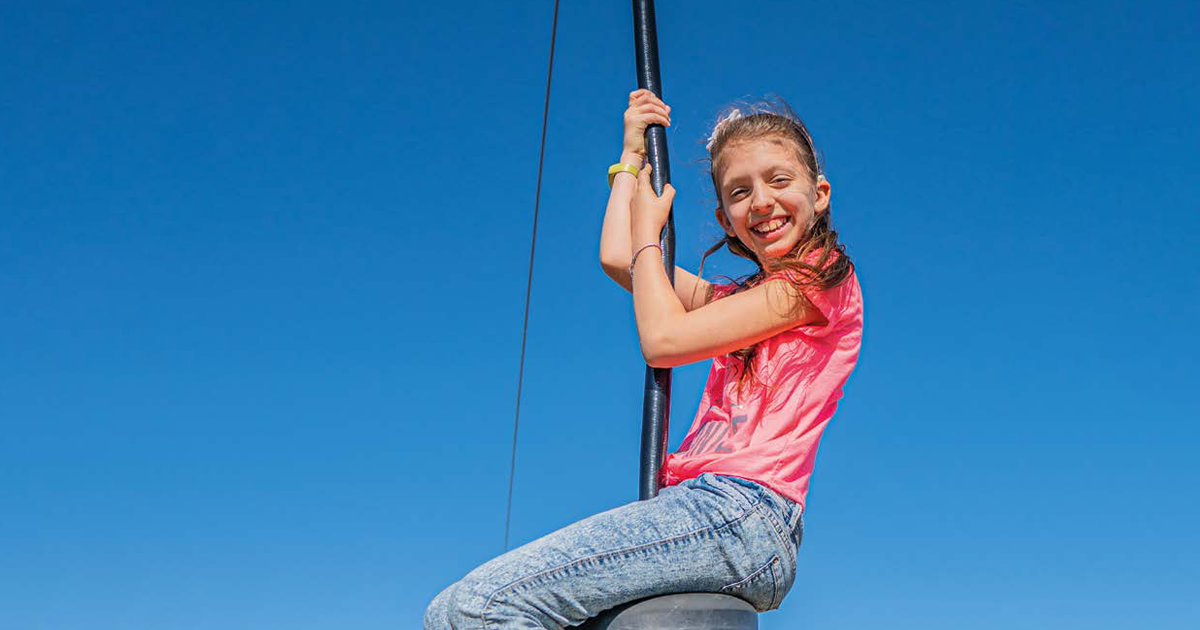 Girl on a swing with blue sky behind her