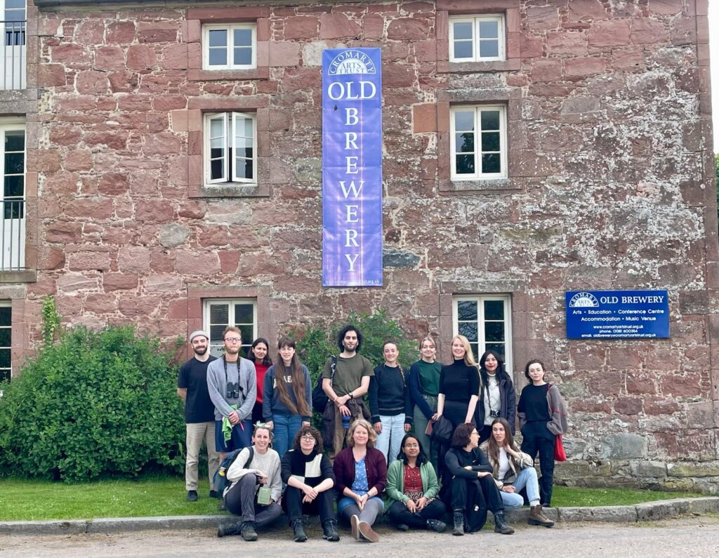 Photo of retreat participants standing together in the foreground, with the venue in the background. 