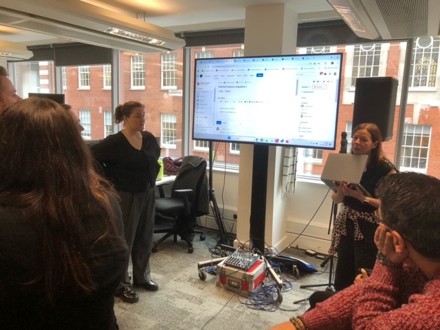 Group of peopl stand around a screen discussing an IT plan