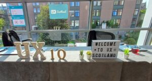 The reception desk at UX Scotland 2025 with ‘UX’ letters, a number 10 for the event’s anniversary, a welcome sign and artificial plants