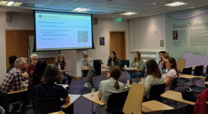 A group of staff sit in a circle in a lecture hall having a discussion