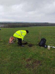 A person in high-vis jacket digging in a field.