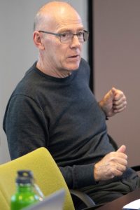 Prof. David Porteous sat at a meeting table with an arm resting on his chair