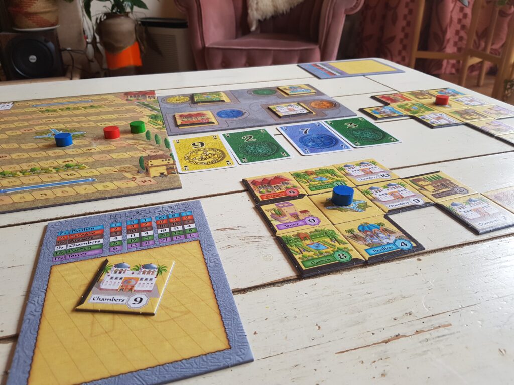 Board game laid out on white table. blue pieces stacked and cards laid out of vary colours