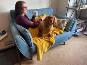 Chloe sitting on a blue sofa with Bonny at her side