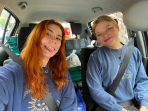 Two girls in a car delivering food packages.