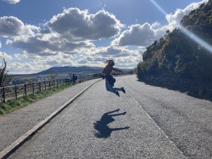 Alexa jumping in the middle of the road on a sunny day
